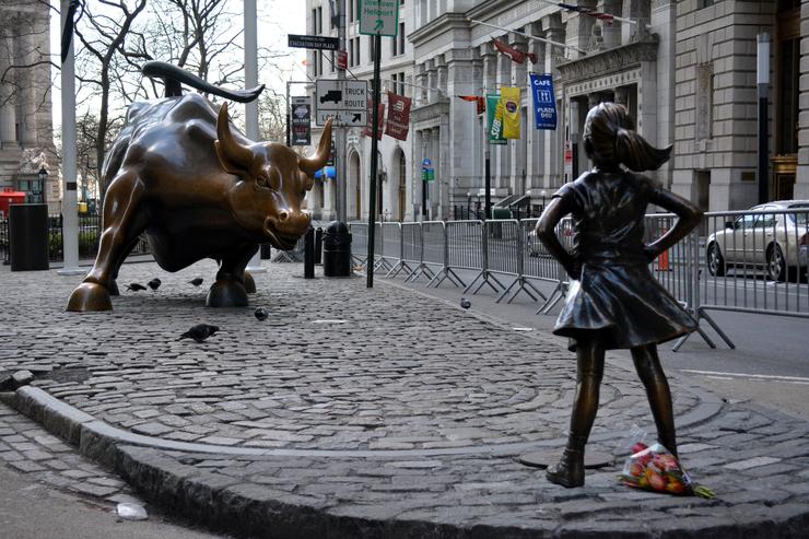 `The Fearless Girl` statue facing the Charging Bull on Wall Street.