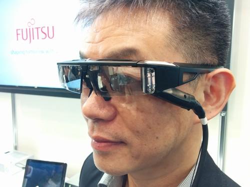 Mitsuru Sugawara, CEO of QD Laser, shows off prototype smartglasses in Tokyo on Tuesday. The glasses house a small laser projector that projects imagery from a front-facing camera or a mobile device onto a user's retina. The glasses could help people with vision loss. 