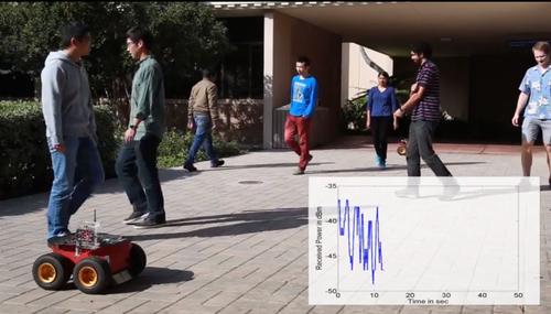 Researchers at the University of California, Santa Barbara have done experiments showing that Wi-Fi signals traveling between wheeled robots (front left) can be used to estimate the number of people in an area. The graph on the lower right shows the received Wi-Fi signal. 